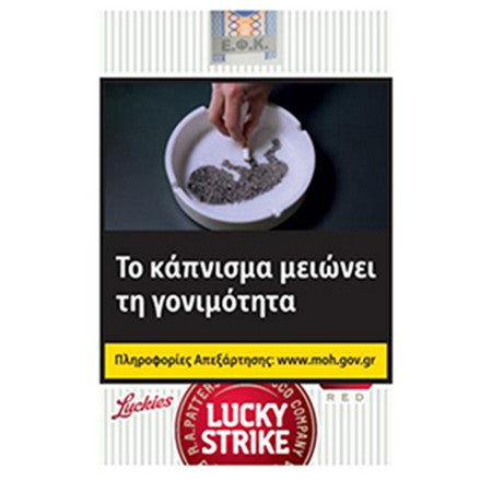 Lucky Strikes 'Red' cigarette tax poster in Greek, featuring a smoking hand in an ashtray, a yellow warning banner, and the Lucky Strikes logo at the bottom.